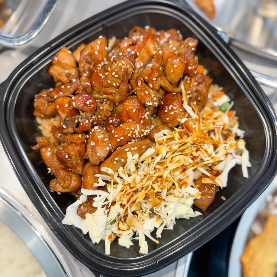 Zing's teriyaki chicken with sesame seeds, shredded cabbage, and sauce in a black bowl.