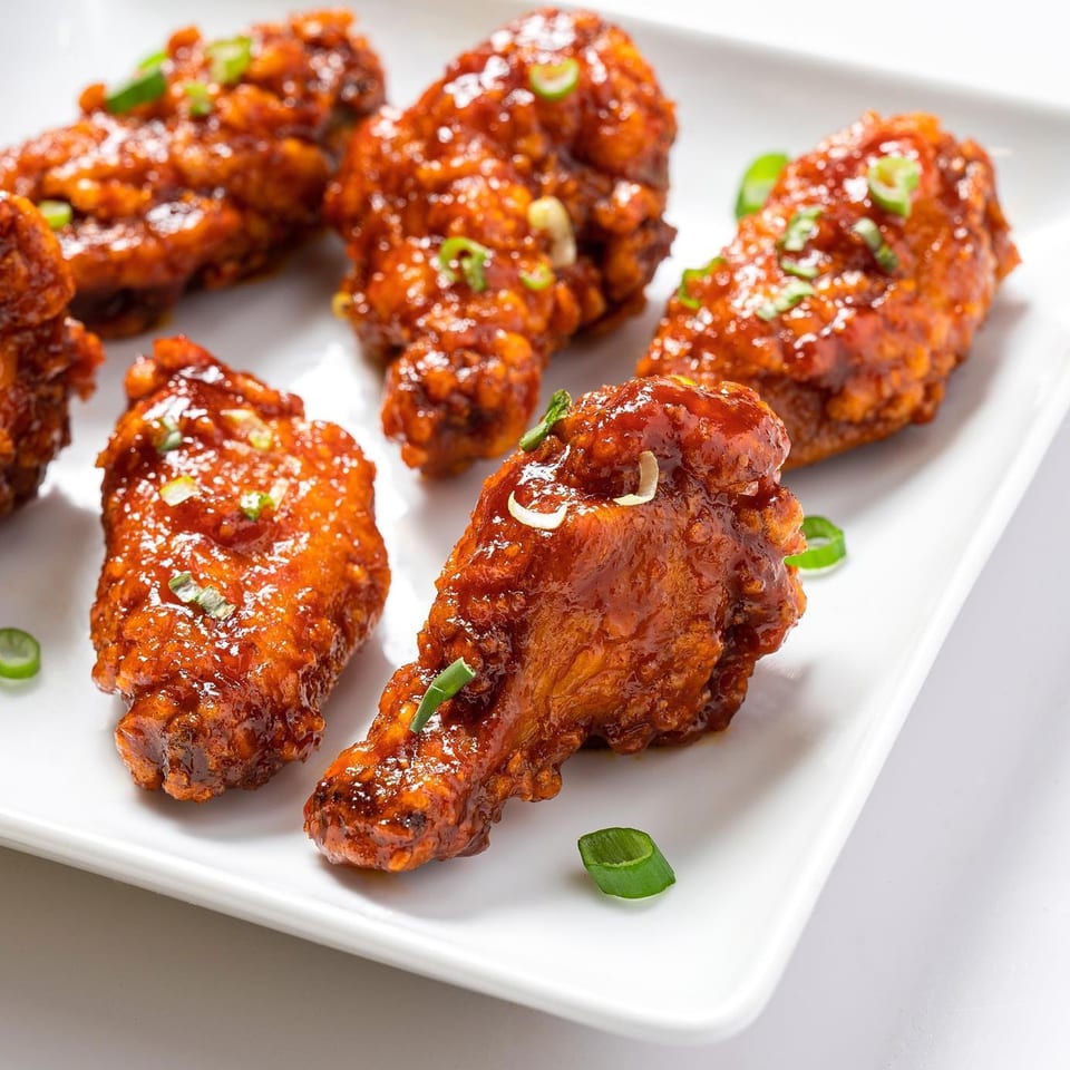 Zing's Asian-fusion chicken wings, glazed in a sweet and spicy sauce, garnished with green onions.