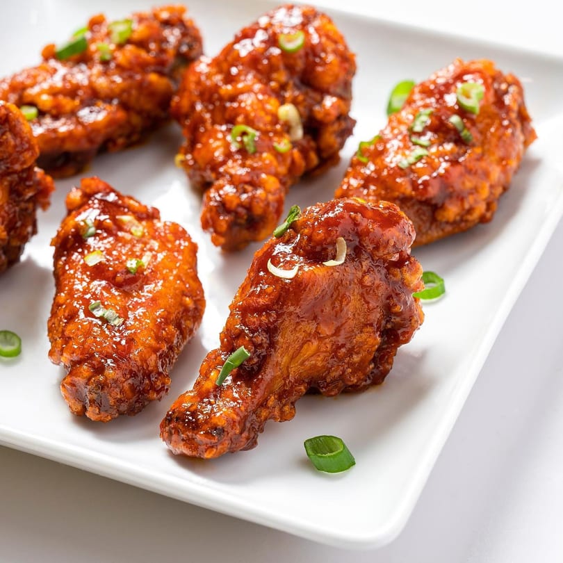 Zing's Asian-fusion chicken wings, glazed in a sweet and spicy sauce, garnished with green onions.