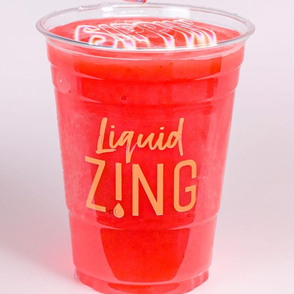 A vibrant red Zing smoothie in a clear plastic cup with "Liquid ZING" printed on it.